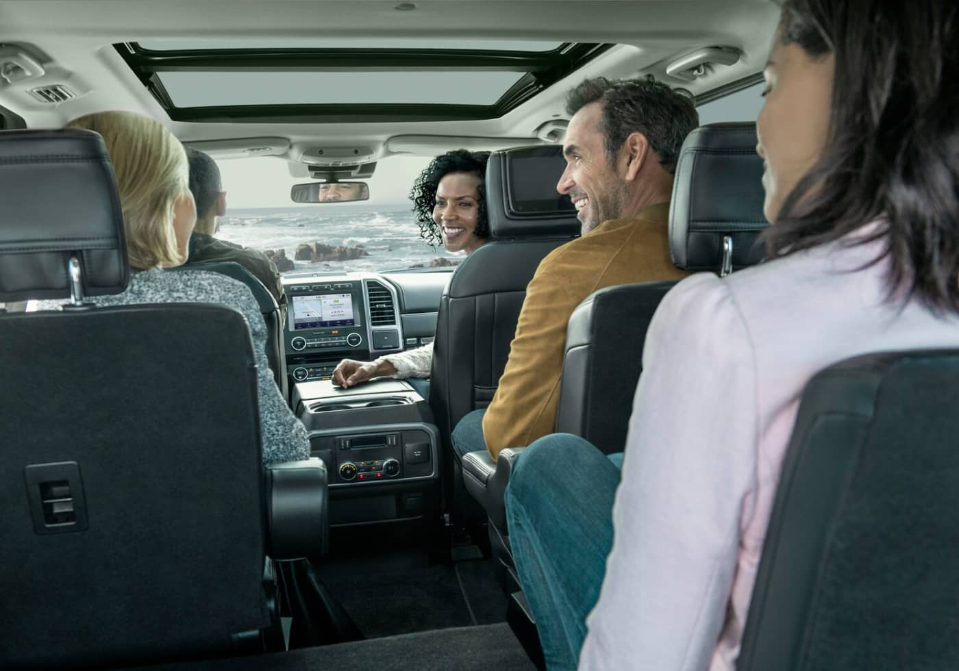 Five people seated in a car, smiling