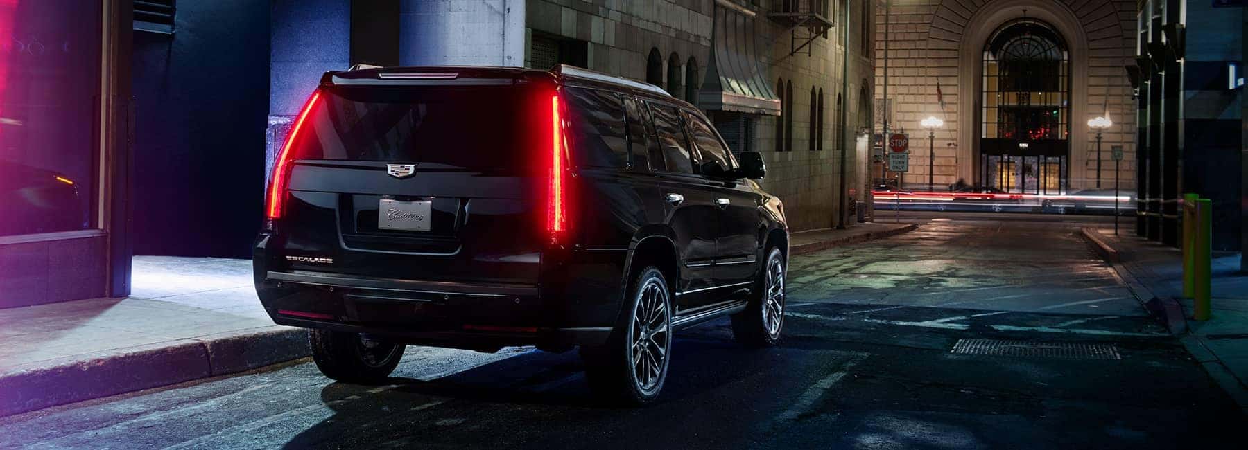 cadillac Black Cadillac Escalade parked in a city at night
