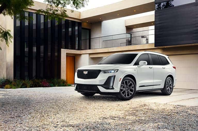 White Cadillac XT5 parked in the driveway of a modern home